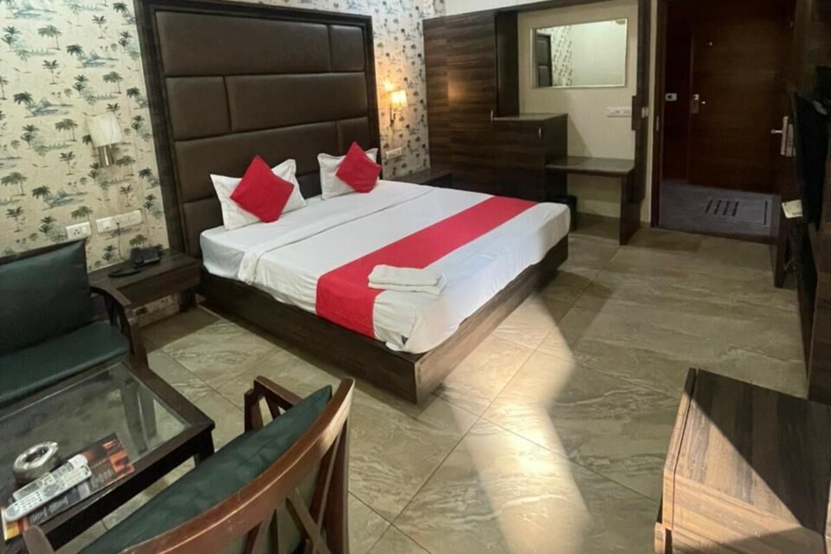 Quarto de hotel com cama, escrivaninha, cadeira, guarda-roupa e espelho.