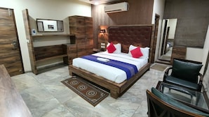 Een slaapkamer met een bed, een bureau, een stoel, een kledingkast en een airconditioning.