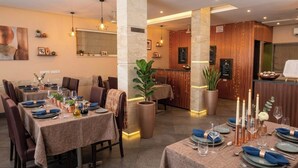 Een restaurant met gedekte tafels, een receptiebalie en een grote potplant.