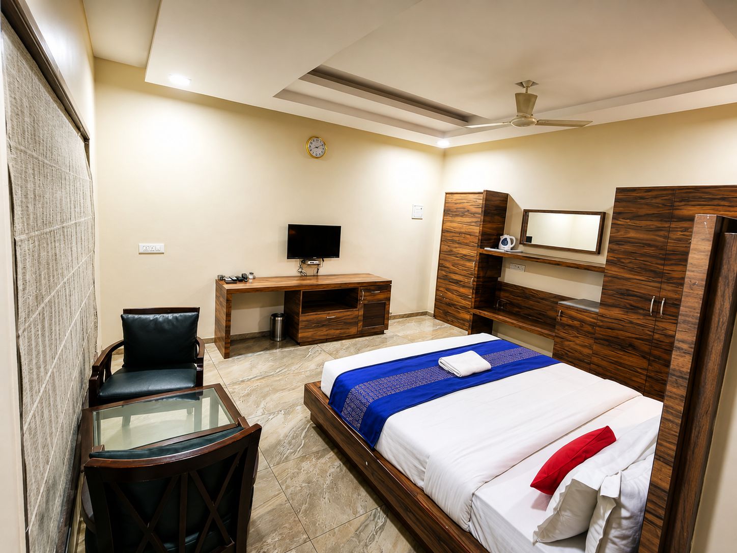 Ein Hotelzimmer mit Bett, Schreibtisch, Stuhl, Fernseher und Kleiderschrank.