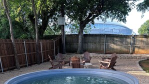 A backyard with a swimming pool, wooden deck, and outdoor furniture.