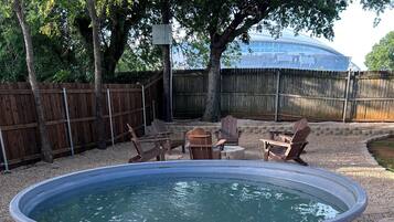 Un jardin avec une piscine, une terrasse en bois et du mobilier d’extérieur.