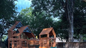 A wooden playground structure with a slide and climbing elements.