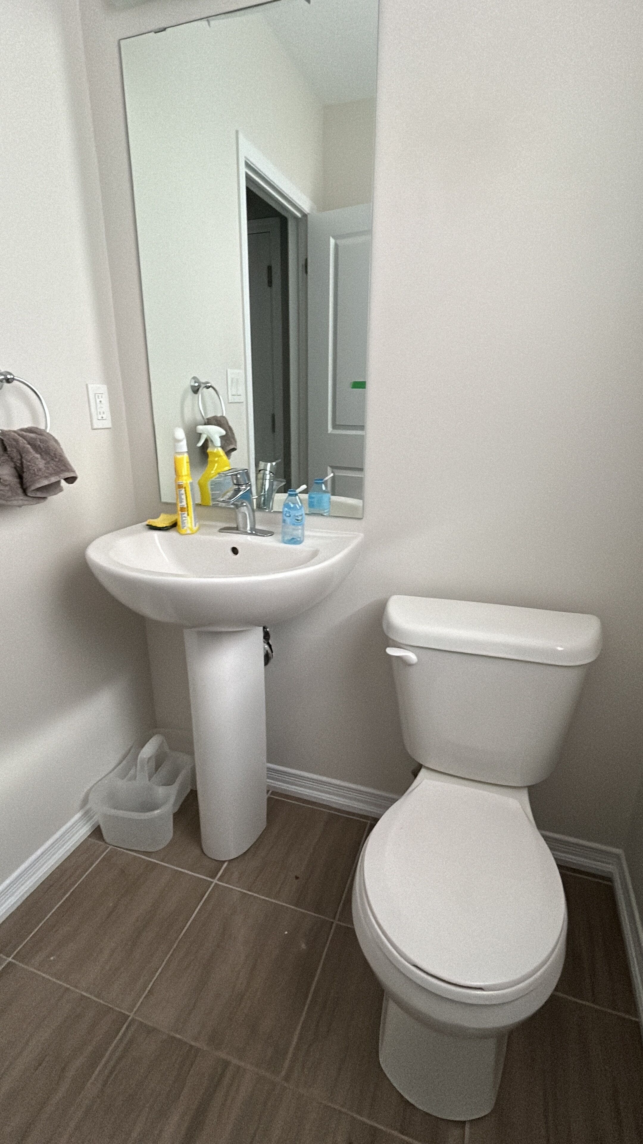 Une salle de bain avec un lavabo blanc, des toilettes et un miroir. On trouve des articles de toilette sur le lavabo.