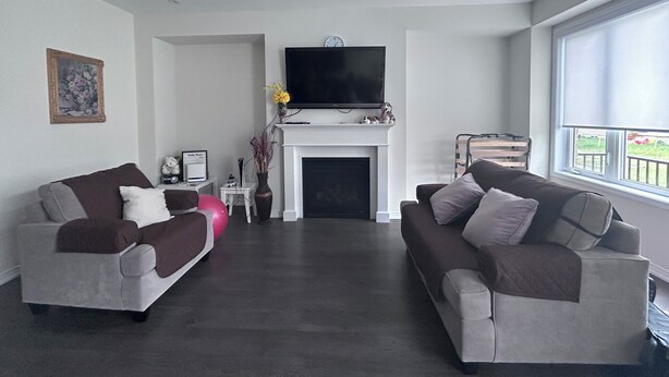 Ein modernes Wohnzimmer mit zwei Sofas, einem Kamin, einem Fernseher und einem großen Fenster.