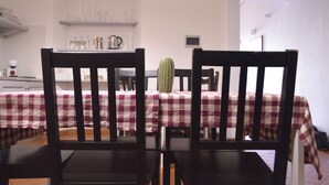 Een zithoek met twee houten stoelen, een tafel met een geruit tafelkleed, en een cactus op de tafel.