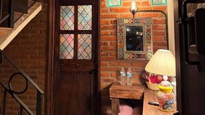A staircase with a wooden door, a small table with a lamp, and a wall with a decorative tile. - La Casona de Los Angeles de San Juan (Taxco)