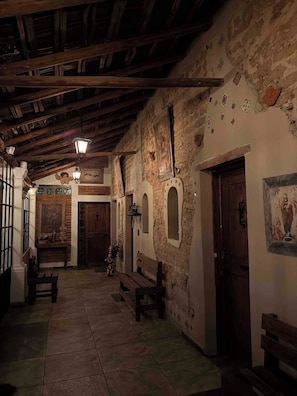 A corridor with wooden beams, stone walls, and benches. - La Casona de Los Angeles de San Juan (Taxco)