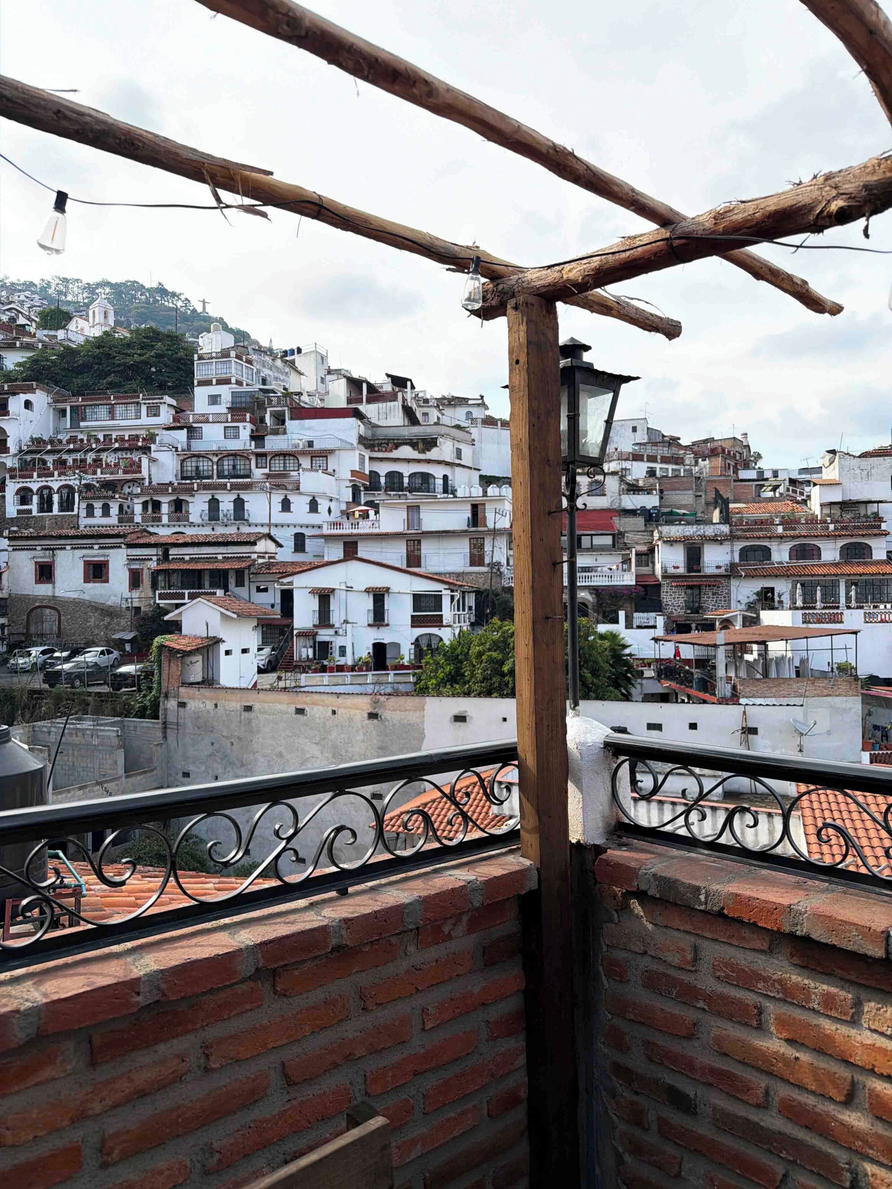 Uma varanda com vista para uma área urbana densamente construída, com telhados de terracota e edifícios brancos.