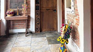 A rustic interior with exposed brick walls, a wooden door, and a tiled floor. - La Casona de Los Angeles de San Juan (Taxco)