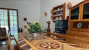 Ein Esstisch mit geometrischem Muster, ein Fernseher und eine Holzkommode mit dekorativen Tellern.