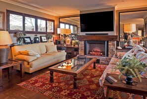 A living room with a sofa, coffee table, fireplace, and a television mounted on the wall.