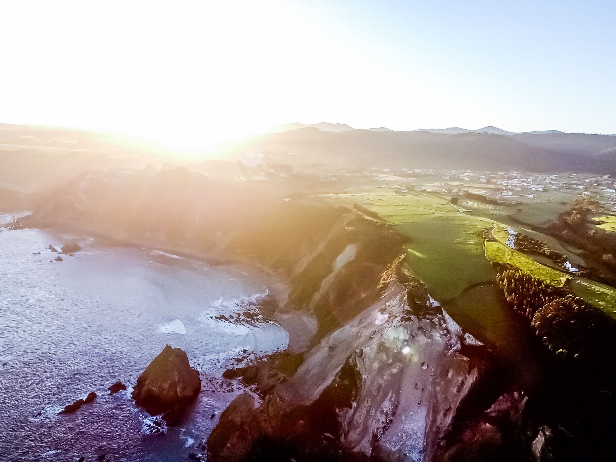 Un paysage côtier caractérisé par une formation rocheuse imposante, une plage et un terrain de golf.