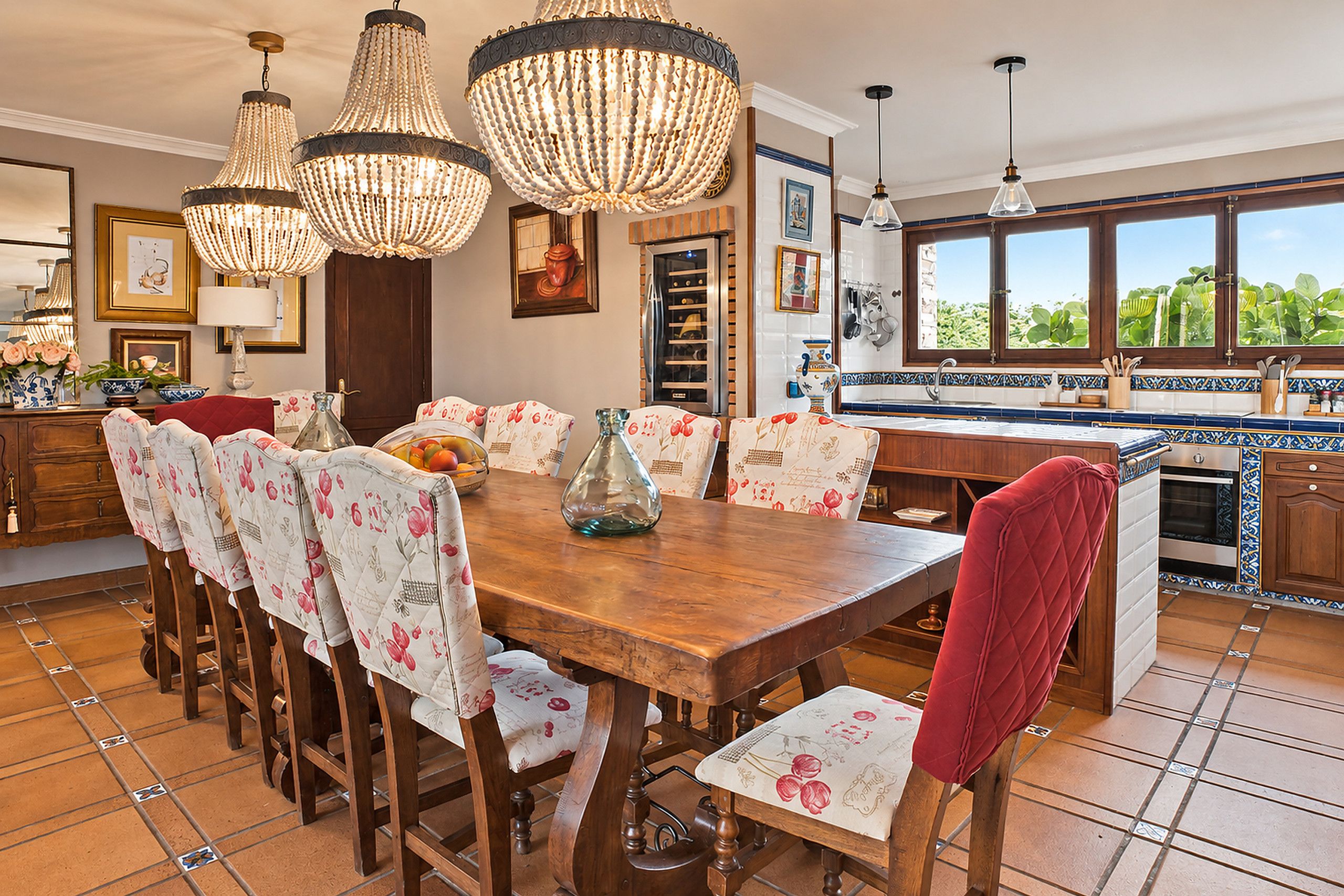 A dining area with a wooden table, floral chairs, and a red upholstered chair.