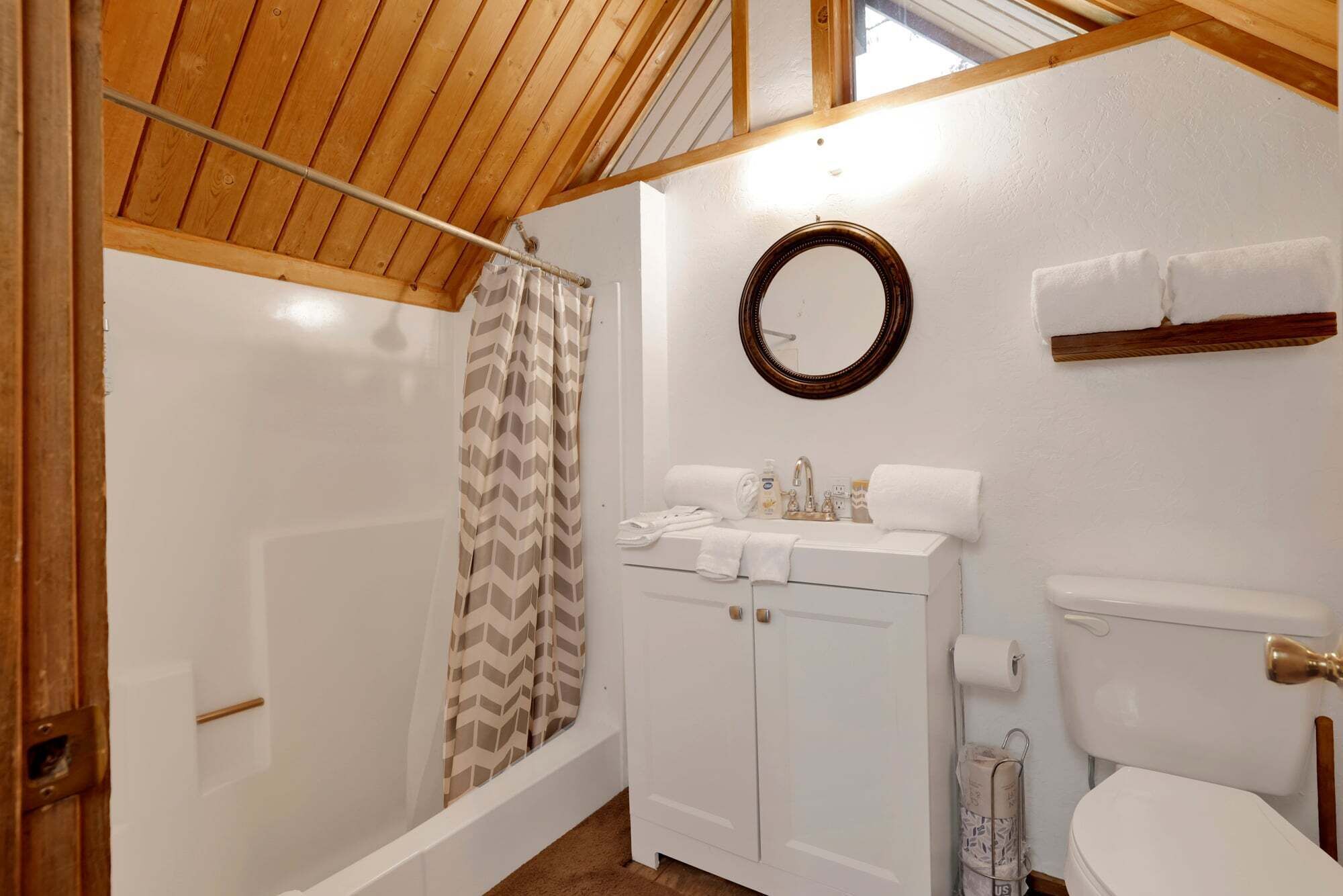 Un baño con ducha, inodoro, lavamanos y espejo.
