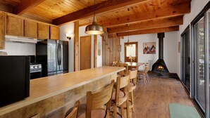 A wooden interior with a kitchen, dining area, and fireplace. - Resting Falcon#2661 (Big Bear City)