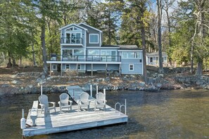 Ein mehrgeschossiges Haus mit Steg und Stühlen an einem Fluss.