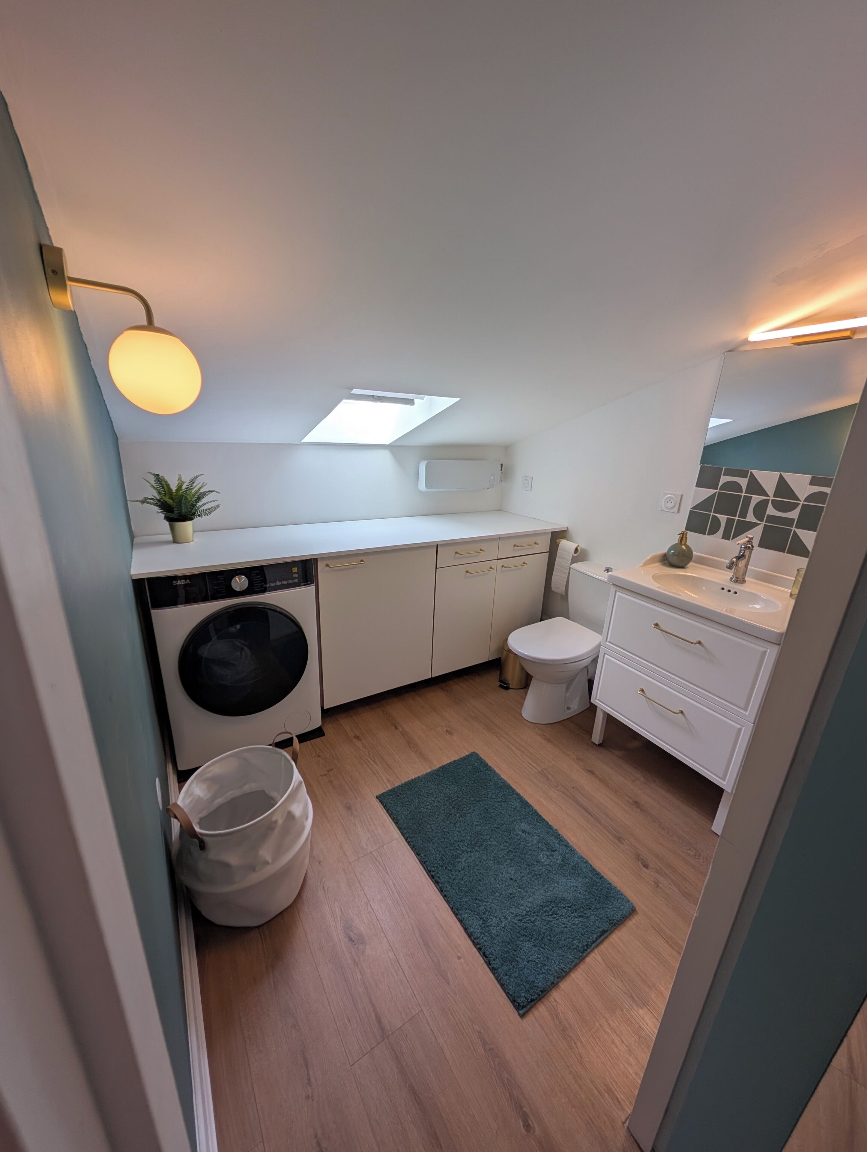 A compact kitchen with a washing machine, a sink, and a toilet.