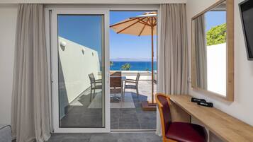 A room with a sliding glass door leading to a balcony with a table, chairs, and an umbrella.