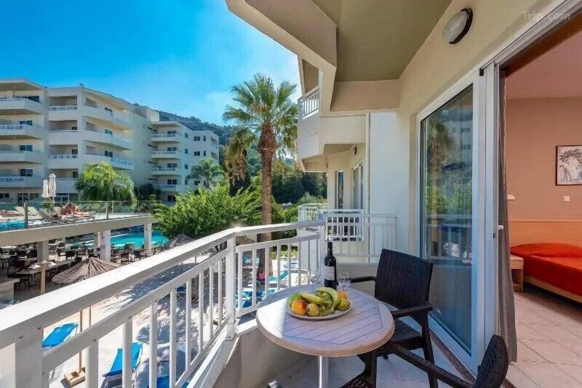 A balcony with a table, chairs, and a fruit bowl.