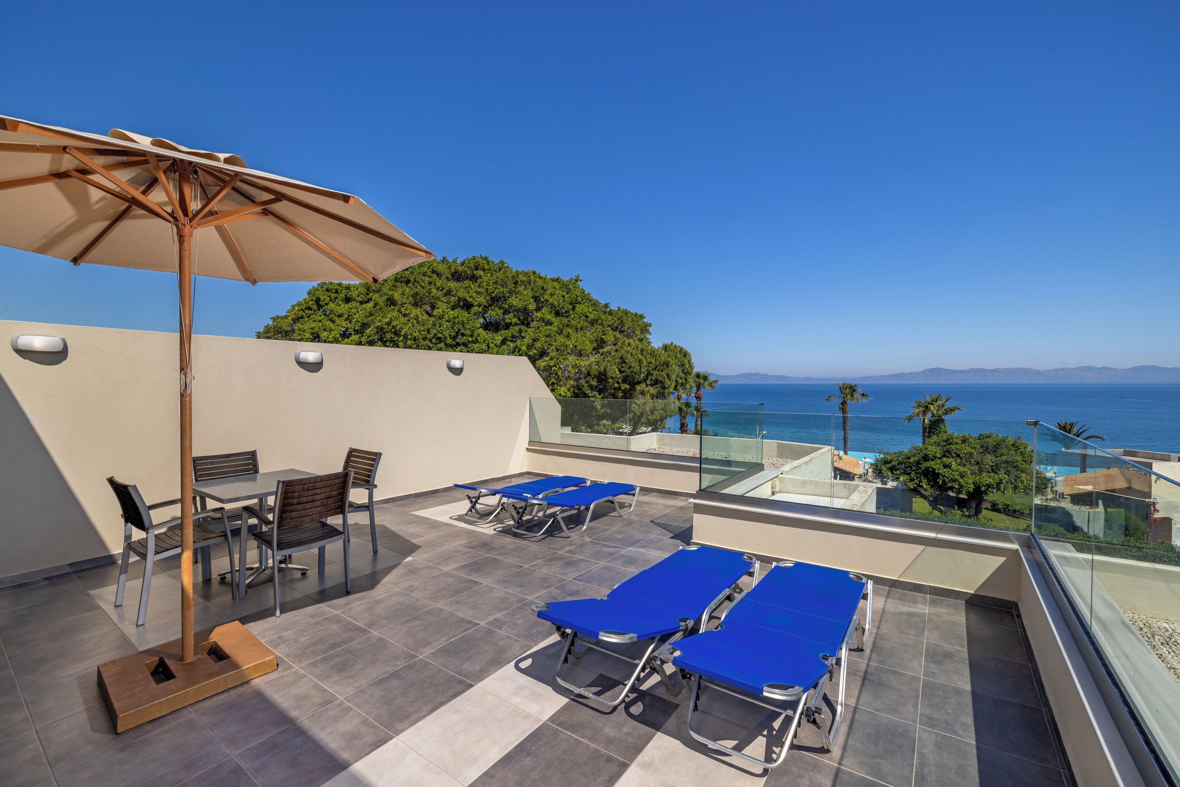 A rooftop terrace with a table and chairs, a sun umbrella, and lounge chairs.