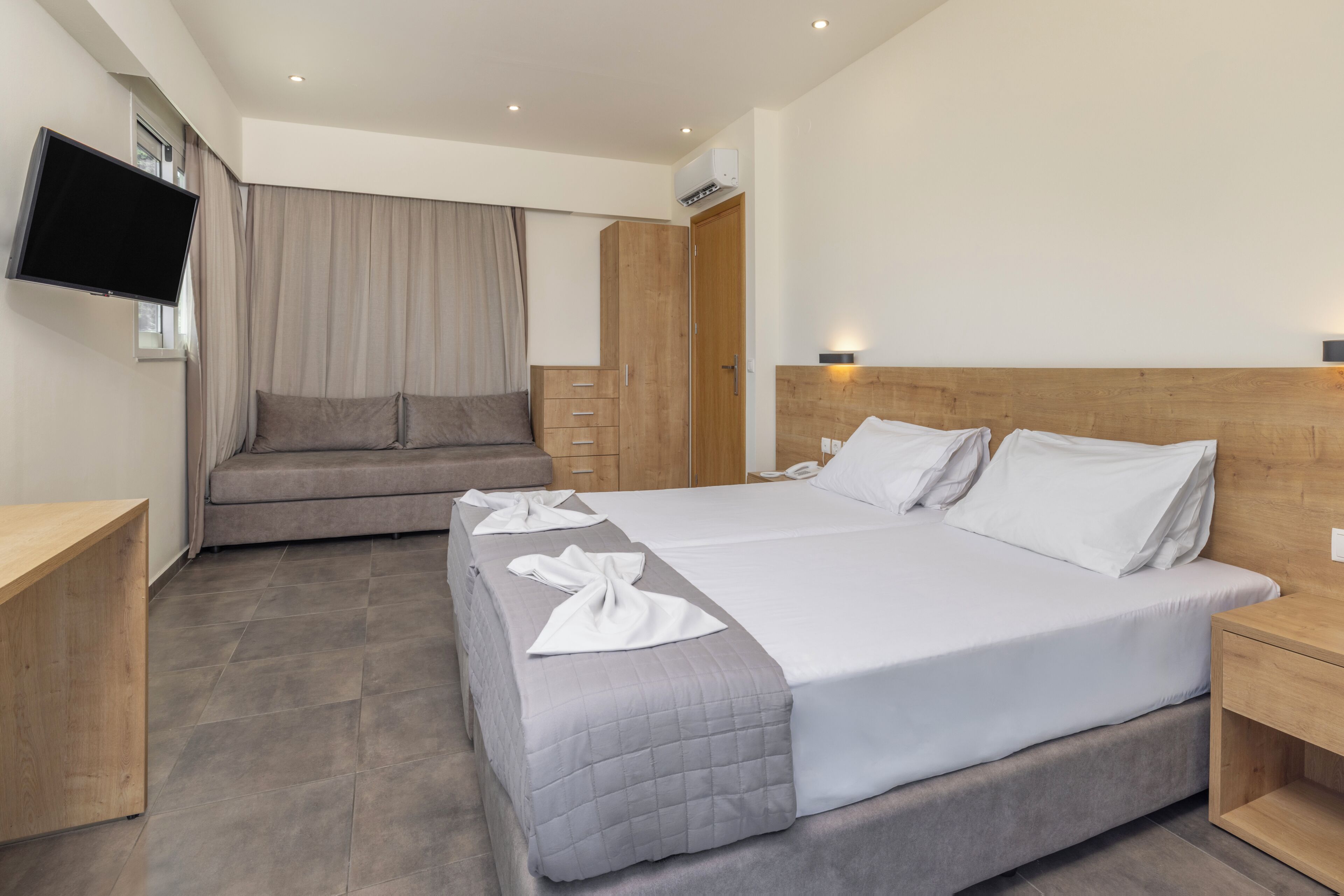 Ett modernt hotellrum med en stor säng, en soffa, en TV och en garderob.