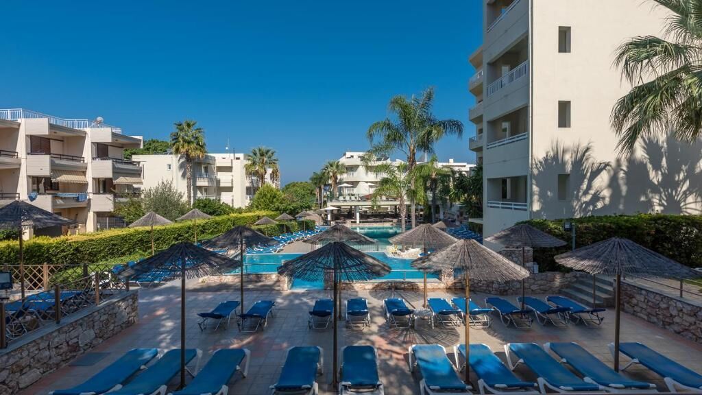 A resort pool area with sun loungers, umbrellas, and a clear blue pool.