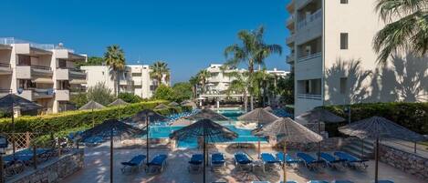 A resort pool area with sun loungers, umbrellas, and a clear blue pool.