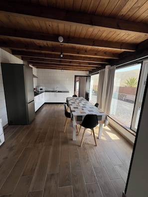A modern kitchen with white cabinets, a wooden floor, and a dining area with a table and chairs.