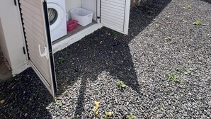 Un'area lavanderia con lavatrice, stendibiancheria e un piccolo contenitore per la biancheria.