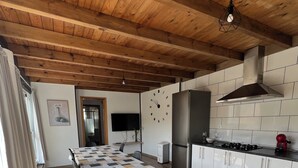 Una cucina moderna con mobili bianchi, piano cottura in acciaio inossidabile e soffitto in legno.