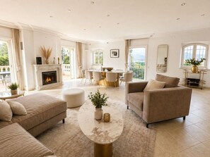 Un salon spacieux avec une cheminée, un coin repas et un balcon offrant une vue agréable.