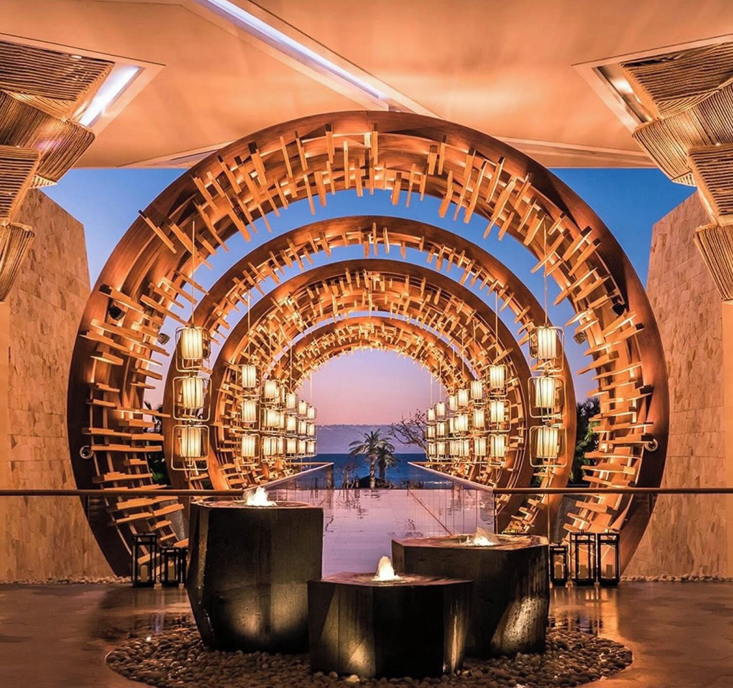 Une structure architecturale circulaire, dotée de plusieurs niveaux d’assises et d’éclairage, qui surplombe une étendue d’eau.