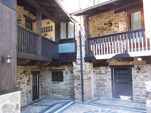 A courtyard with stone walls, wooden balconies, and a stone floor.