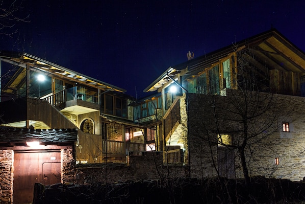 A multi-story building with a balcony, a stone wall, and a wooden door.