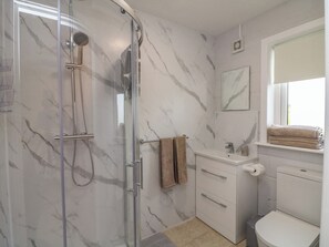 A bathroom with a glass-enclosed shower, a white sink, a toilet, and a towel rack. - Radharc an Hook @ Estuary Bliss (Duncannon)