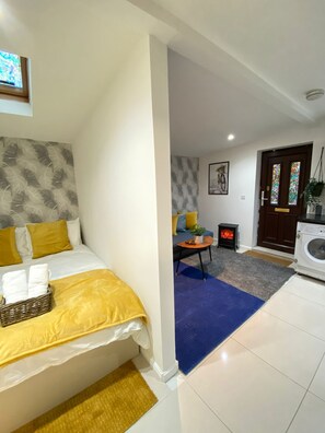 A hotel room with a bed, a small table with a plant, a heater, and a washing machine. - Tower Bridge Cozy Studio Up To 4 People (London)
