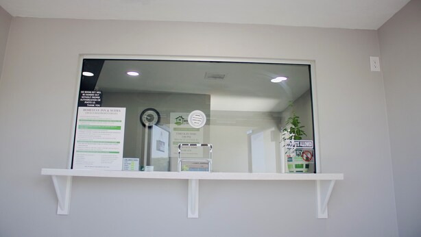 A reception area with a check-in counter, a clock, and a sign indicating check-in times. - HomeStay Inn & Suites (Oklahoma City)