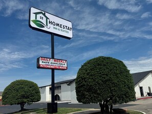 A sign for Homestay Inn & Suites with a daily/weekly rate, free WiFi & cable, and a kitchenette room. - HomeStay Inn & Suites (Oklahoma City)