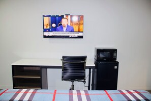 A room with a bed, a desk, a chair, a television, and a microwave. - HomeStay Inn & Suites (Oklahoma City)
