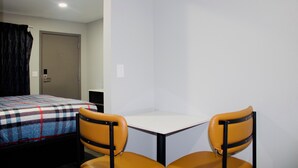 A hotel room with a bed, two chairs, a table, and a door. - HomeStay Inn & Suites (Oklahoma City)
