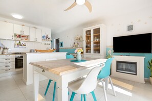 A modern kitchen with white cabinets, a wooden island, and a built-in TV.