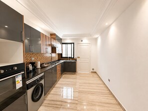 A modern kitchen with a washing machine, a stove, and a coffee maker. - Marsa Cube House Beachfront Living in La Marsa (La Marsa)
