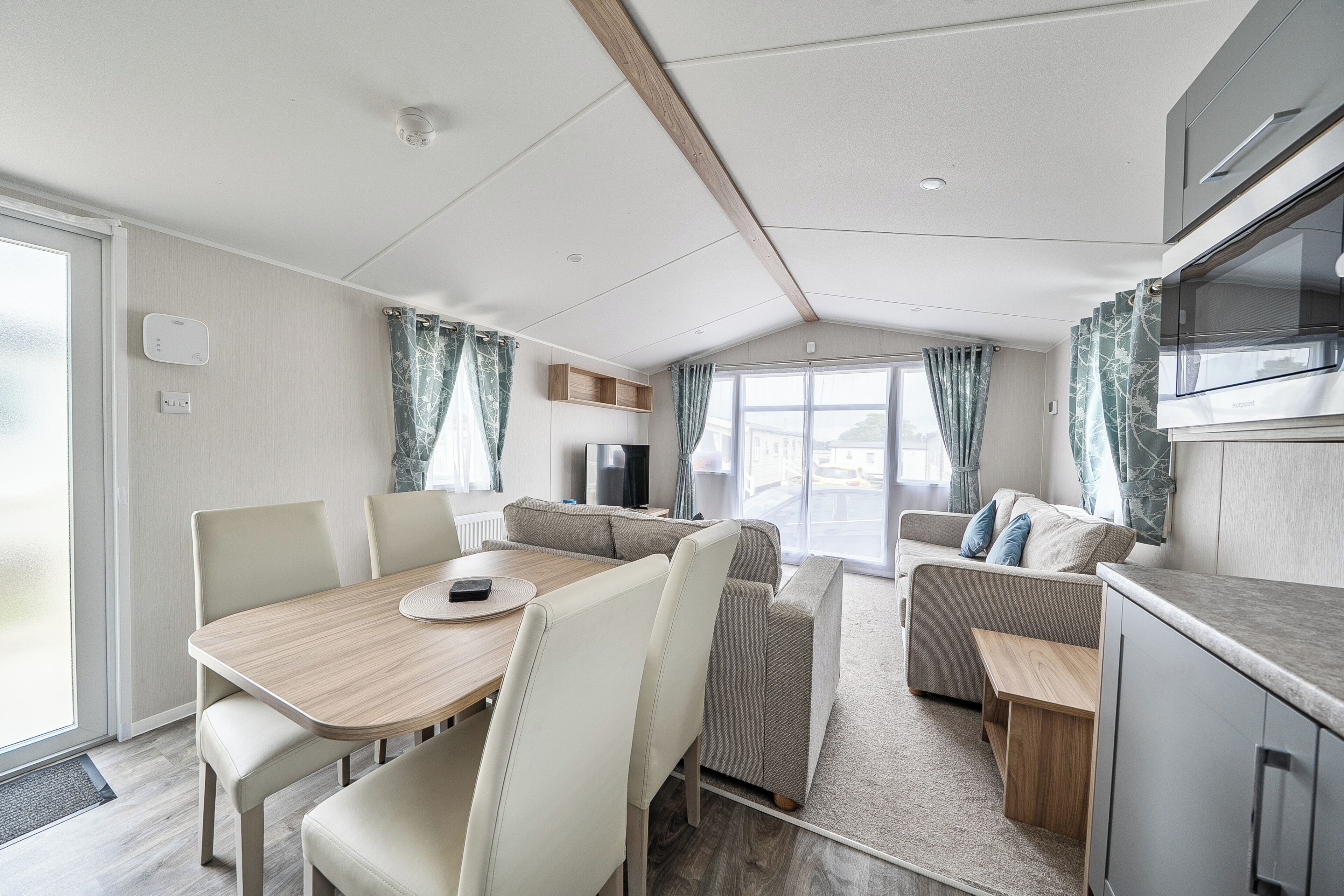Interior moderno de autocaravana con comedor, asientos y una kitchenette.