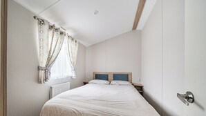 Ein Schlafzimmer mit einem Bett, einem Nachttisch, einem Fenster mit Vorhängen und einer Tür.