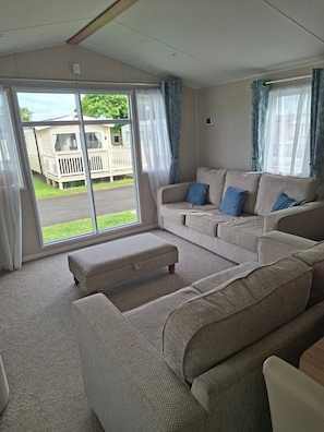 A living room with a sofa, ottoman, and curtains.