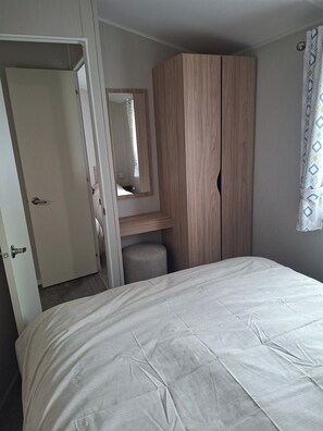 A bedroom with a bed, a wardrobe, a mirror, and a door.