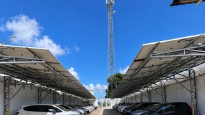 A parking lot with cars, a tall communication tower, and a clear blue sky.