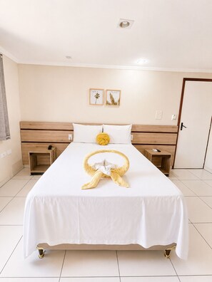A hotel room with a large bed, two bedside tables, a door, and two wall-mounted pictures. - Hotel Nacional (ARAPIRACA)