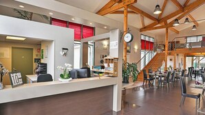 A hotel reception area with a desk, chairs, a clock, and a staircase leading to upper floors. - Zenao Appart'hôtels Sainte-Soulle (Sainte-Soulle)
